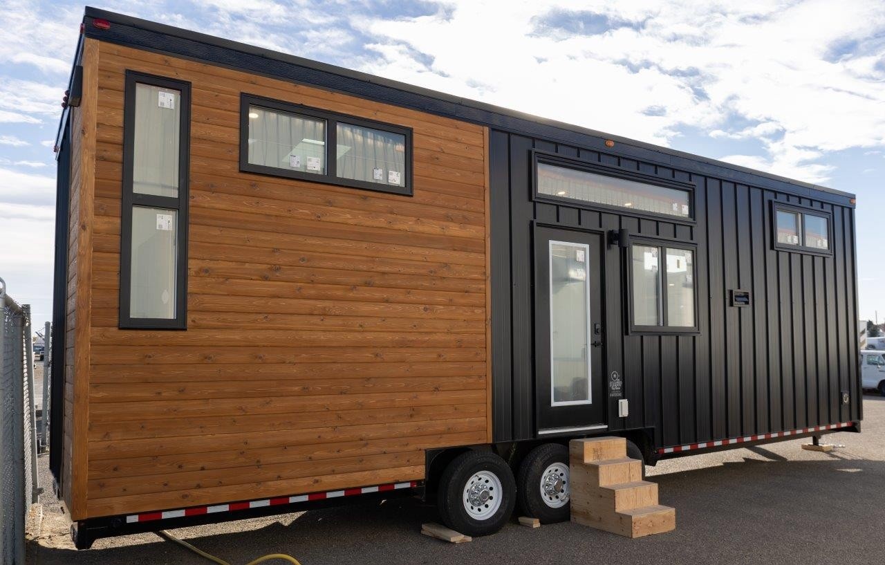 Tiny Home on Wheels with black windows and metal siding and wood tng
